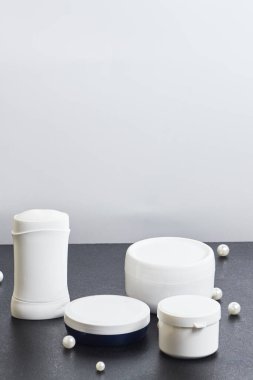 Gri arka planda banyo tüpü deodorant incileri için beyaz kozmetik kavanozları. çoklu uzay. Model modeli. düşey yönelim