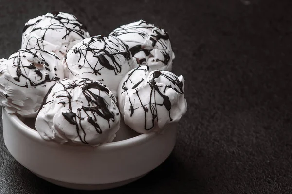 As bolas de sorvete brancas em uma chapa vazaram o chocolate em uma mesa preta. close up, espaço de cópia — Fotografia de Stock