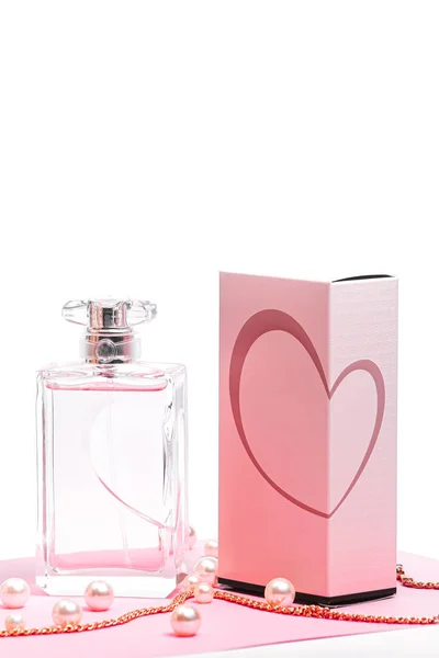 Różowa butelka perfum z perłami i złotym łańcuszkiem i pudełko na różowym prześcieradle na białym tle. widok na bot, orientacja pionowa — Zdjęcie stockowe