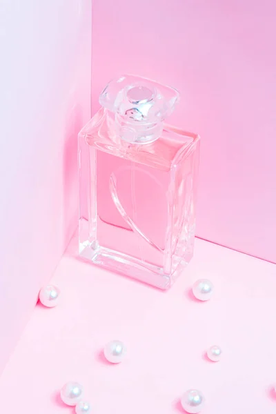 Różowa butelka perfum z perłami na różowym tle przestrzeń do kopiowania. widok na bot, orientacja pionowa, makieta — Zdjęcie stockowe
