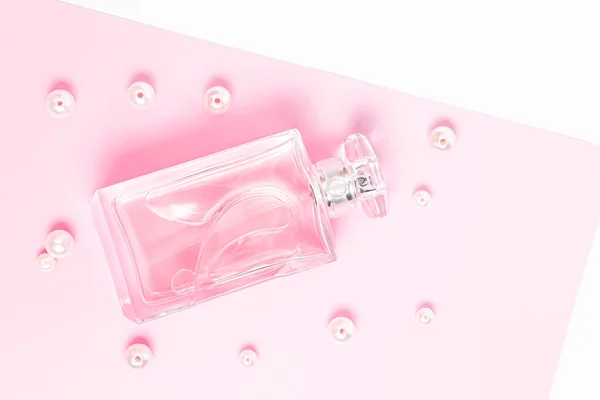 Roze parfumflesje met parels op een roze vel op een witte achtergrond kopieerruimte. bovenaanzicht, model — Stockfoto