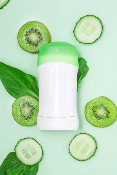 Beyaz kavanoz terleme önleyici, yeşil kapaklı deodorant salatalık, kivi ve nane arkaplanda taze yapraklar. Kapat, kopyala, taklit et