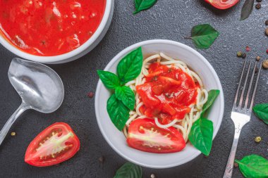 Tabakta soslu spagetti ve siyah bir masada fesleğenli domates sosu. kopyalama alanı, üst görünüm, yatay yönelim, kapat