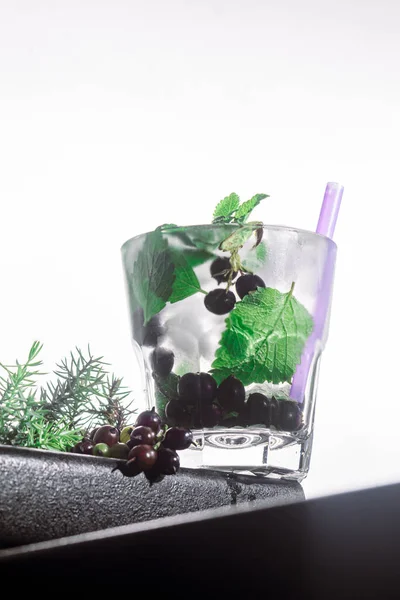 Cocktail di bacche, menta, ghiaccio in un bicchiere di rox sul bordo di un bancone del bar sfondo bianco. vista bot, primo piano, orientamento verticale — Foto Stock