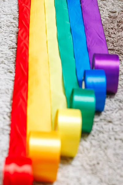 Ribbons in the color of the lgbt rainbow flag in bobbins are rolled out on the carpet using how to celebrate homosexuals, gay, lesbian and concepts — Stock Photo, Image