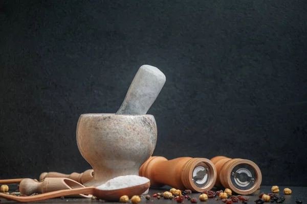 Stone mortar with pepper and wooden spoon with spices on the table, side view, copy space — Stock Photo, Image