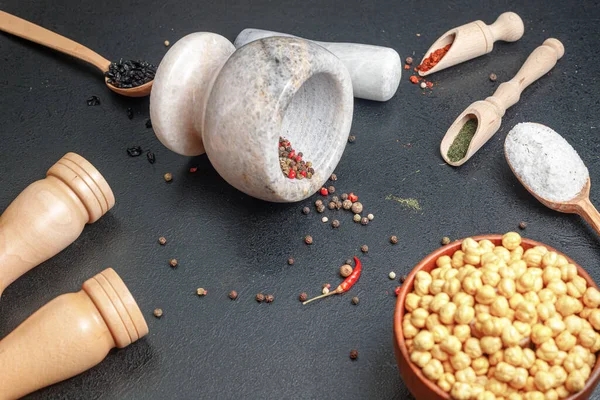 Malta di pietra caduta con pepe e cucchiai di legno con spezie sul tavolo — Foto Stock