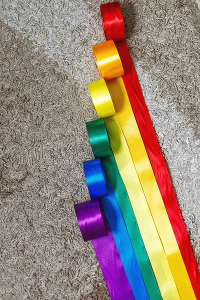 Band i färgen på lgbt regnbåge flaggan i bobbins rullas ut på mattan med hjälp av hur man firar homosexuella, homosexuella, lesbiska och begrepp — Stockfoto