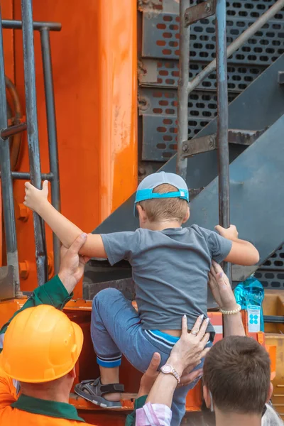 people help a little boy, a child climb an industrial ladder