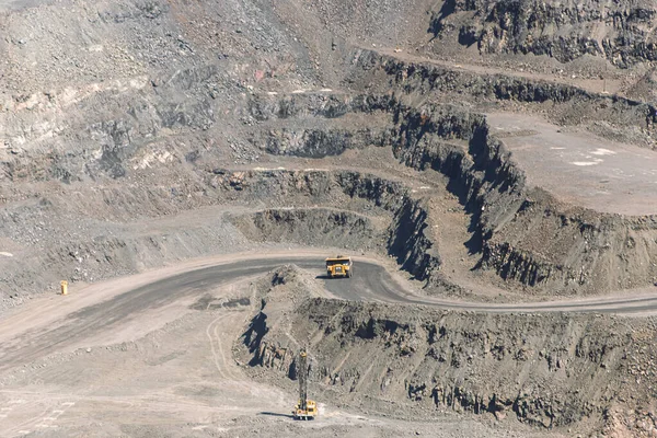 iron ore quarry dump truck moves on the road of stepped terraced terrain, mining industry, mining and quarrying equipment.