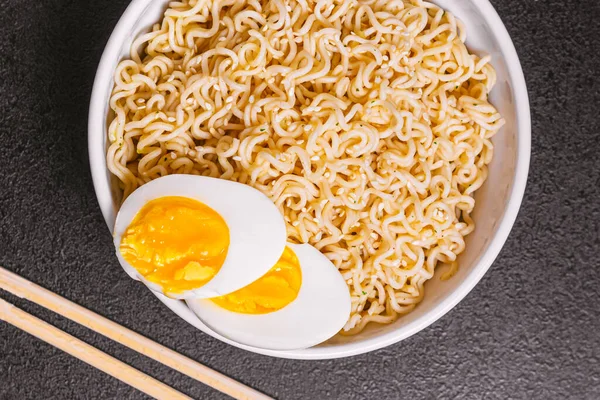 Noodles σε ένα πιάτο με σουσάμι σπόρους μπαμπού μπαστούνια, βραστά αυγά σε ένα μαύρο τραπέζι γκρο πλαν. Φλατ λι. αντίγραφο χώρου. — Φωτογραφία Αρχείου