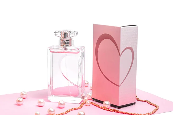 Różowa butelka perfum z perłami i złotym łańcuszkiem i pudełko na różowym prześcieradle na białym tle. widok bota — Zdjęcie stockowe