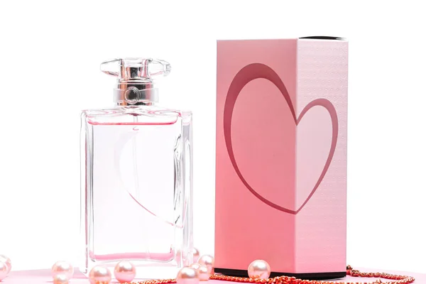 Рожева пляшка парфумів з перлами і золотим ланцюжком і коробка на рожевому аркуші на білому фоні копіювання простору. вигляд бота — стокове фото