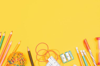 Okul konseptine, sarı arka plandaki okul gereçlerine, fotokopi alanı olan düz yere.