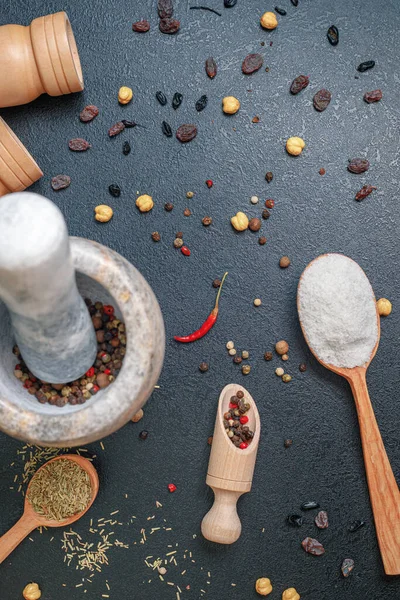 Malta di pietra con pepe e cucchiai di legno con spezie sul tavolo, lei piatta, primo piano — Foto Stock