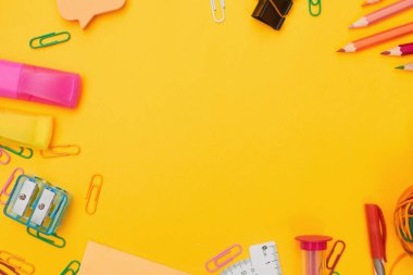 Okul konseptine, sarı arka plandaki okul gereçlerine, fotokopi alanı olan düz yere.
