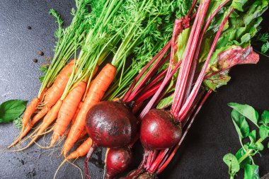Yeşil saplı havuç ve siyah bir masada yaprakları olan pancar. Boşluğu kopyala, kapat,