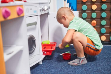 Çocuk mutfağında oynayan küçük bir çocuk.