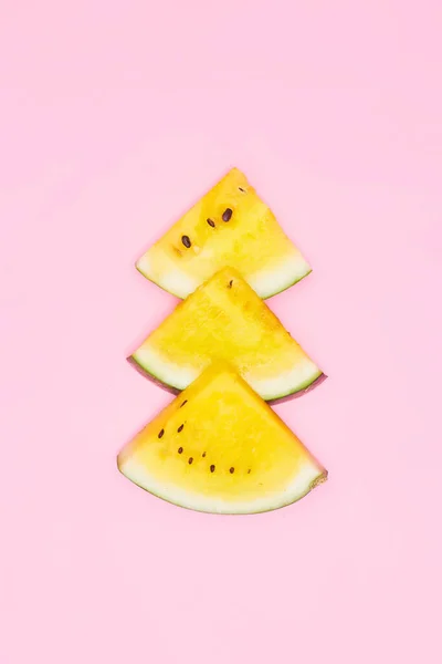 slices of yellow watermelon on a pastel pink background, copyspace, layout
