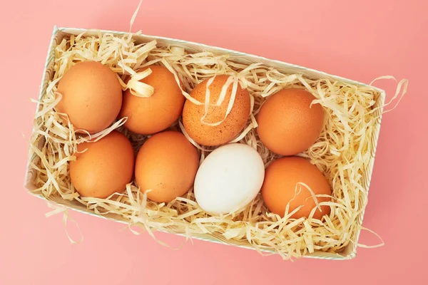 Kycklingägg i en låda på en rosa pastell bakgrund, kopior av utrymme, flatlay — Stockfoto