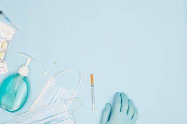 Mavi arka plan covid-19 koronavirüs önleme kavramının üzerinde ellerini yıkamak için kullanılan alkol dezenfektan jel şişeli tıbbi yüz maskesi düzdü.