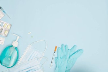 Mavi arka plan covid-19 koronavirüs önleme kavramının üzerinde ellerini yıkamak için kullanılan alkol dezenfektan jel şişeli tıbbi yüz maskesi düzdü.