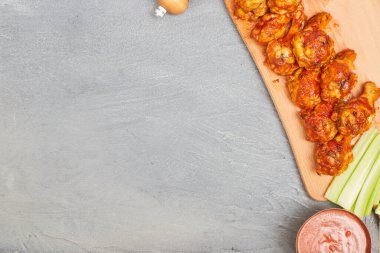 Ahşap bir tahtanın üzerinde tavuk kanatları beton bir arka planda kereviz, üst manzara, kopyalama alanı