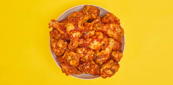 Buffalo chicken wings in a bowl on a yellow background, copy space — Stock Photo, Image