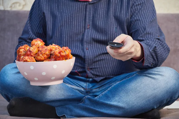 Homem assistindo tv no sofá com um prato de asas de frango Buffalo, espaço de cópia — Fotografia de Stock