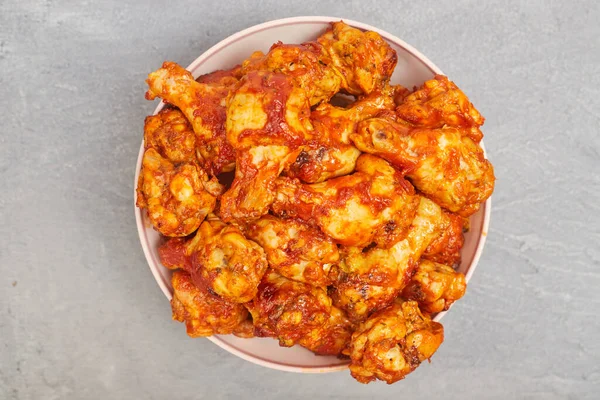 Alitas de pollo de búfalo en un plato sobre un fondo de hormigón gris, espacio para copiar —  Fotos de Stock