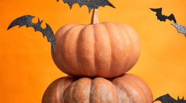 Turuncu arkaplanda Cadılar Bayramı balkabakları ve yarasaları kopyalama alanı