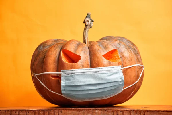 Zucche di Halloween in una maschera medica su uno spazio di copia di sfondo arancione — Foto Stock
