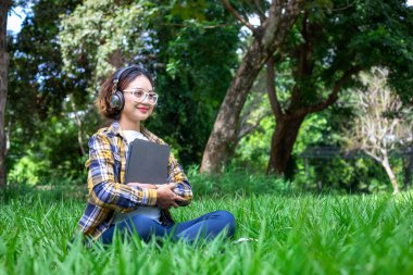 Güzel bir kadın parkta çimlerde mutlu mesut otururken müzik dinlerdi..