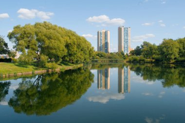 Güzel şehir parkı, gölü ve ufukta iki yeni bina var..