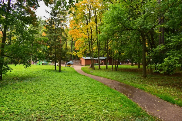 stock image Zoo in a leisure park with a nearby playground. Green grass and partially yellowing leaves of trees harmoniously harmonize with their color scheme.