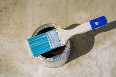 Açık banka boyaları ve beton arka planda mavi fırça. Boya, yapıştırıcı, vernik ya da farklı yüzeylerdeki diğer malzemeler. Kopyalama alanı olan üst görünüm
