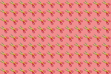 Açık plastik, sarı ve kırmızı makasın renksiz deseni. Pastel pembe arka planda. Yukarıdan bakınca. Düz yatıyordu