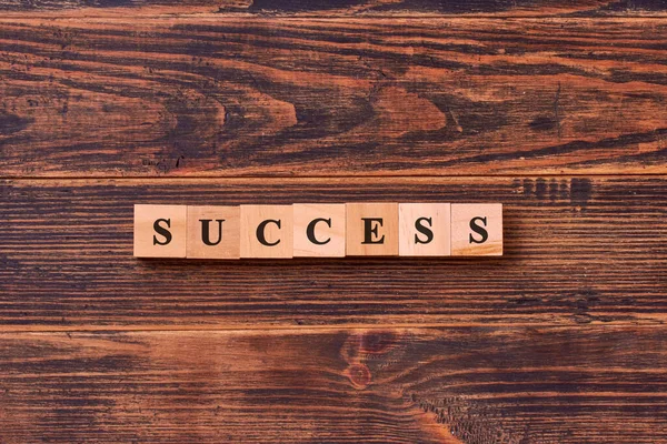 Koyu ahşap arka planda tahta küplerden yapılmış başarılı kelime harfleri. İş, başarı, hırs, başarı ve kazanma konsepti.