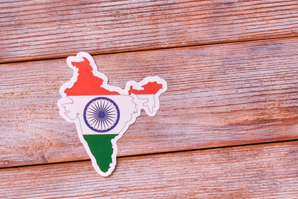 Country border outline map of INDIA. Shape and national flag on white wooden background. Copy Space for design