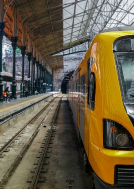 Sarı tren Porto tren istasyonunda biniş için bekleyen, bir tarafında boş raylar ve arka planda bir tünel ile