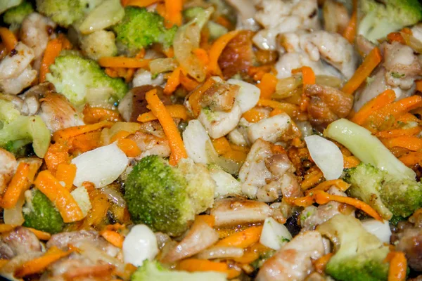 meat broccoli carrots onions garlic with sesame seeds all together in a pan. looks like a background