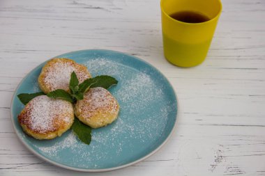 Mavi tabakta cheesecake ve açık ahşap arka planda kahve.