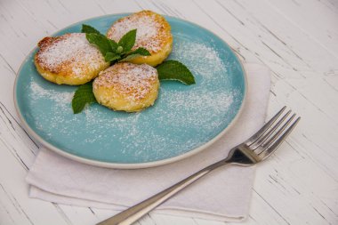 Mavi bir tabakta çatallı cheesecake ve hafif ahşap arka planda pamuk bez.