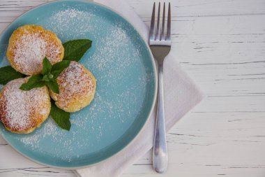 Mavi bir tabakta çatallı cheesecake ve hafif ahşap arka planda pamuk bez.