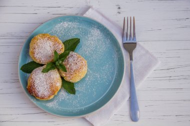 Mavi bir tabakta çatallı cheesecake ve hafif ahşap arka planda pamuk bez.