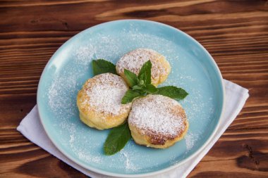 Mavi tabakta cheesecake, kahverengi ahşap arka planda pamuk bez