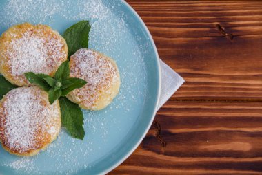 Mavi tabakta cheesecake, kahverengi ahşap arka planda pamuk bez