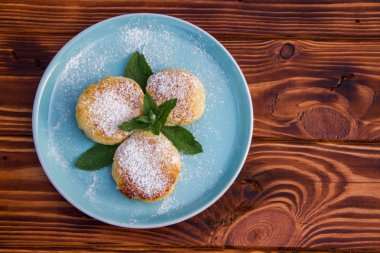 Kahverengi ahşap arka planda mavi tabakta cheesecake