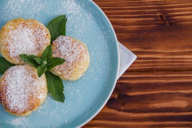 Mavi tabakta cheesecake, kahverengi ahşap arka planda pamuk bez