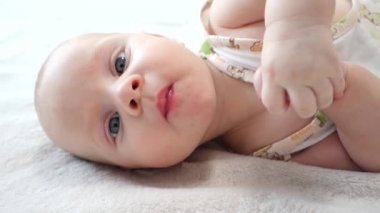 güzel bebek yatakta yatıyordu ve kameraya bakıyor